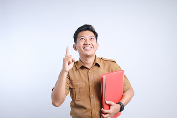 Male Asian civil servant in brown uniform pointing up while holding document file