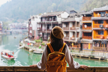 Young female tourist looking at the beautiful landscape of Feng Huang Ancient Town, The famous...