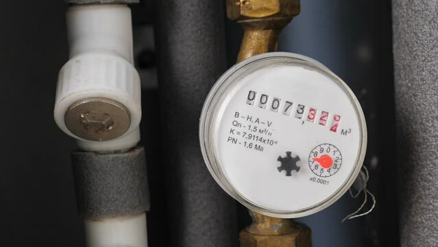 Water meter in box with pipes built into the wall . Water consumption measuring device. Closeup