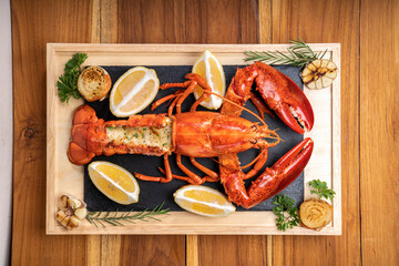 Grilled Lobster with Cheese on black plate, Grilled Canadian Lobster on wooden background.