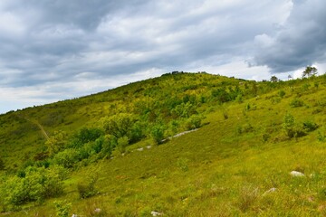 Hill top at Kras in Slovenia lit by sunlight with clouds in the sky - obrazy, fototapety, plakaty