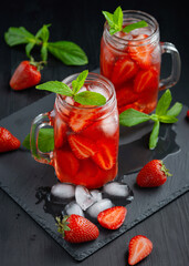 Fresh strawberry cocktail. Fresh summer cocktail with strawberry and ice cubes. Glass of strawberry drink on dark background