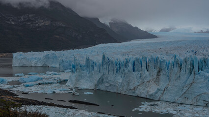 An amazing glacier stretches between the mountain slopes to the horizon. A mass of blue ice with...