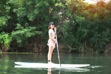 Beautiful young woman on a stand up paddle board on a water
