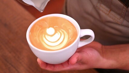 Barista pouring milk making a coffee latte art. People pour milk to making latte art coffee at cafe