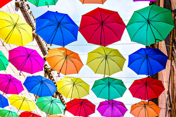 Background of many hanging colorful umbrellas decorating the street of a town