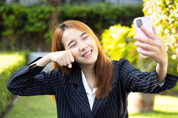 Young and modern office worker woman using smartphone to take selfie mobile photo or making video call with friend