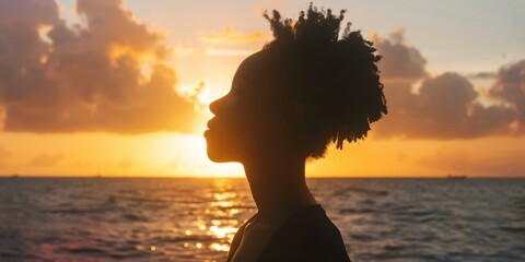 Young African-American woman watching the sunset over the ocean