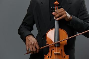 Elegant African American man in suit showcasing a violin on a neutral gray background concept © SHOTPRIME STUDIO
