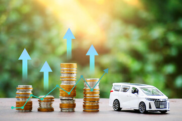 Toy car and pile of coins with a rising graphic arrow on nature background, saving money and...