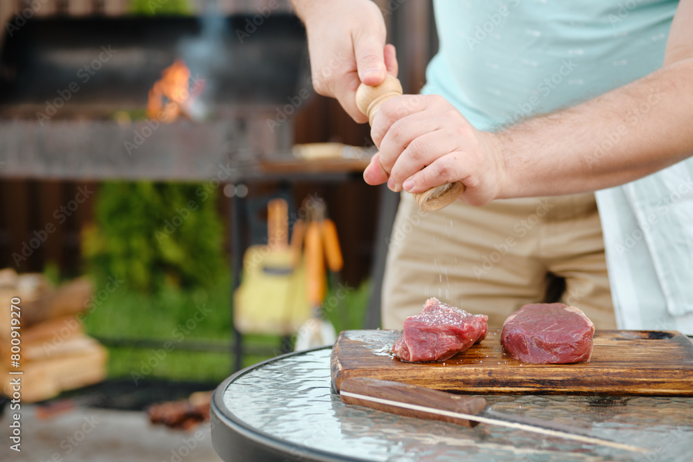 Wall mural Sprinkle salt from hand grinder on raw strip steak