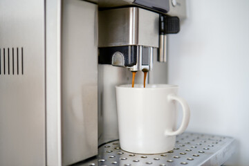 Coffee is poured into a cup from a coffee machine
