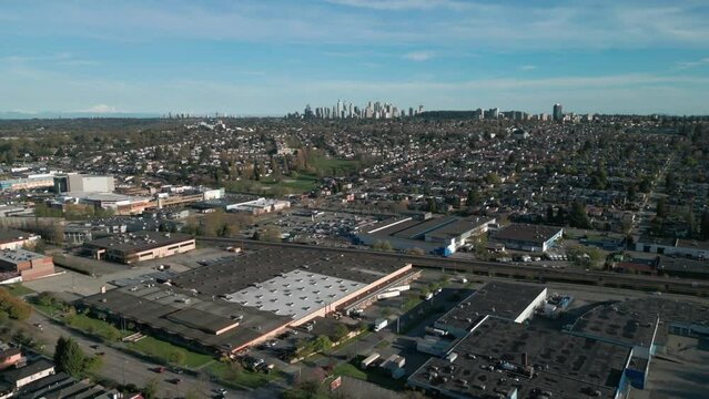 drone shot going backward over burnaby district in east vancouver, vancouver suburban area with burnaby skyscraper in the background on a sunny day, british columbia, canada