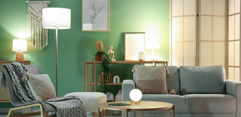 Interior of living room with grey sofa, armchair, coffee table and glowing lamps