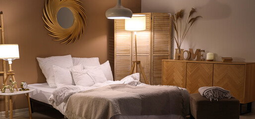 Interior of bedroom with blankets and glowing lamps in evening