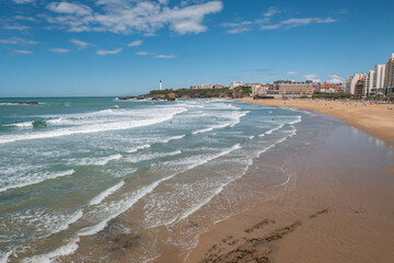 Praia em Biarritz com pequenas ondas e alguns banhistas e surfistas no mar num dia ensolarado - obrazy, fototapety, plakaty