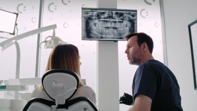 Dentist discussing panoramic digital X-Ray of a patient's teeth