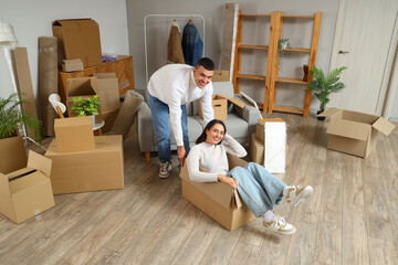 Happy young man and his wife in cardboard box on moving day