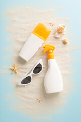 Vertical top view photo of unlabeled SPF containers, fashionable shades, sand, and seashore...