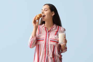 Young woman with glass of tasty milk and croissant on blue background - obrazy, fototapety, plakaty