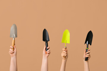 Female hands with different gardening shovels on color background
