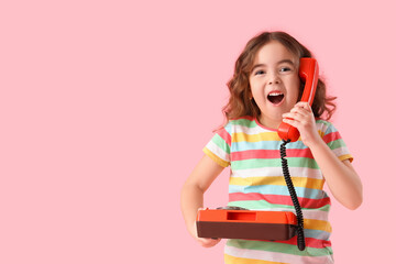 Shocked little girl with retro phone on pink background