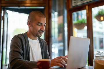 Man, cafe and working with laptop for business, networking and online search for remote work with...