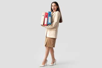 Shocked businesswoman with folders on white background