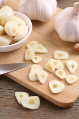 Aromatic cut garlic, cloves and bulbs on wooden table, closeup