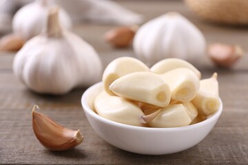 Aromatic garlic cloves and bulbs on wooden table, closeup. Space for text