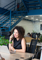 Entrepreneurial woman of 50 years working in a coworking speaking on the cell phone