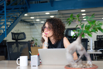 Entrepreneurial caucasian woman working in a coworking pensive