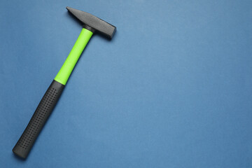 New hammer with rubber handle on blue background, top view. Space for text