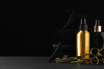 Different hairdresser tools on grey table against black background. Space for text