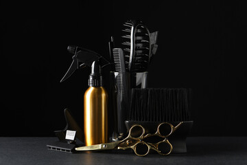 Different hairdresser tools on grey table against black background