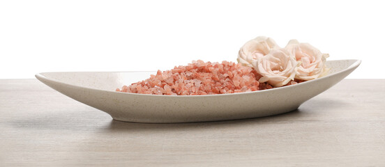 Natural sea salt in bowl and roses on light wooden table against white background