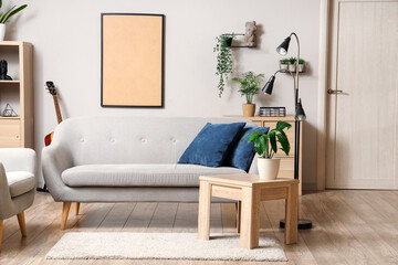 Interior of light living room with grey sofa, table and plants