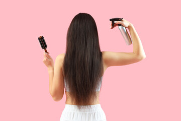 Beautiful young Asian woman with brush and spray on pink background, back view