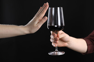 Alcohol addiction. Woman refusing glass of wine on black background, closeup