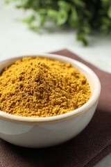 Curry powder in bowl on white table, closeup