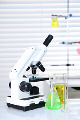 Laboratory analysis. Different glassware with liquids and microscope on white table indoors