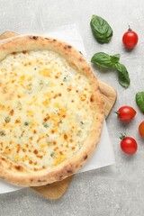 Delicious cheese pizza, basil and tomatoes on light grey table, flat lay