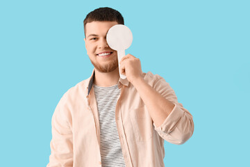Young man with eye occluder on blue background