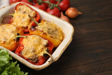 Delicious stuffed peppers in baking dish on wooden table, space for text