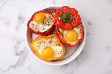 Delicious stuffed peppers with eggs in bowl on white marble table, top view