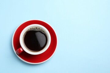 Aromatic coffee in cup on light blue background, top view. Space for text