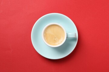 Aromatic coffee in cup on red background, top view