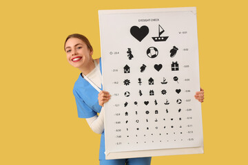 Female ophthalmologist with eye test chart on yellow background