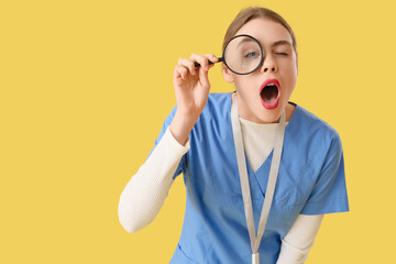 Shocked female ophthalmologist with magnifier on yellow background