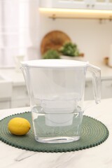 Water filter jug and lemon on white marble table in kitchen